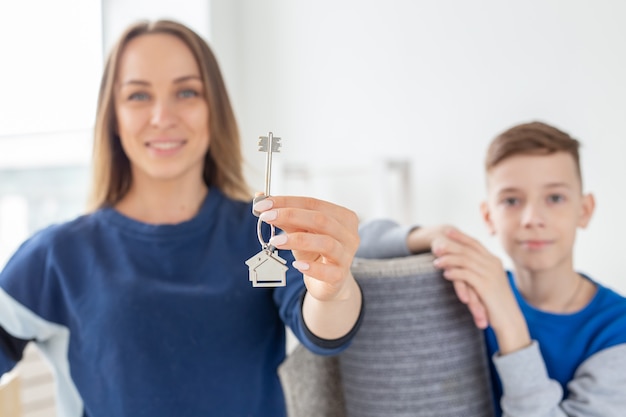 Verschwommene, gut aussehende Mutter und Sohn halten nach der Einweihungsfeier die Schlüssel für eine neue Wohnung in der Hand. Neu