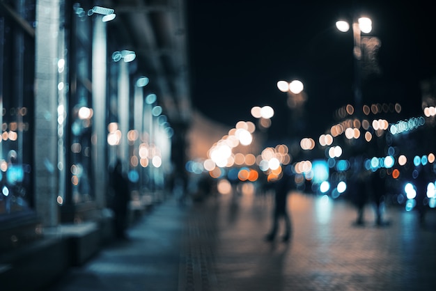 Verschwommene Stadt in der Nacht. Bokeh. Schöner abstrakter Hintergrund mit defocused Gebäuden, Autos, Stadtlichter, Leute