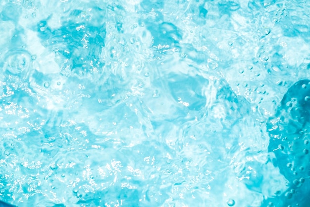 Verschwommene, transparente, blau gefärbte, klare, ruhige Wasseroberflächenstruktur mit Spritzern und Blasen Trendiger abstrakter Naturhintergrund Wasserwellen im Sonnenlicht Wasserhintergrund