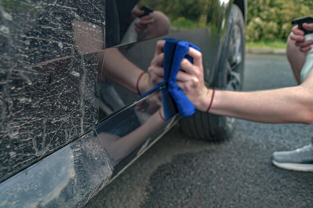 Verschwommener Fokus. Autowaschanlage wischt Autotüren mit der Hand ab. Saubere Spur nach Verschmutzung