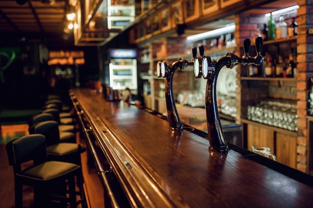 Verschwommener Hintergrund der klassischen Bartheke aus Holz mit leeren Stühlen und Alkohol im Hintergrund