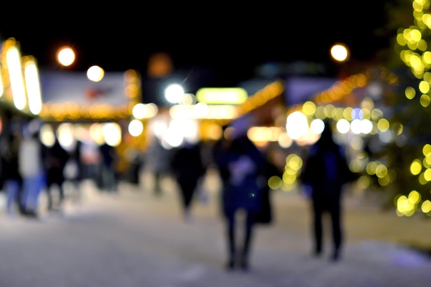 Verschwommener Hintergrund Die Leute gehen in der Winternacht auf den Stadtplatz