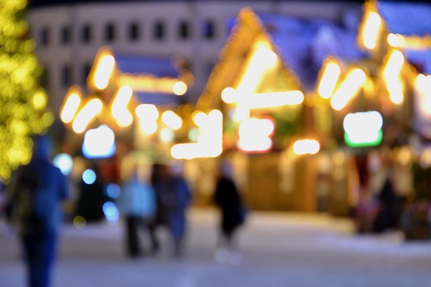 Verschwommener Hintergrund Die Leute gehen in der Winternacht auf den Stadtplatz