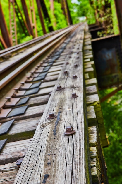 Verschwommener Hintergrund einer Eisenbahnbrücke mit Schrauben und Schrauben auf einem texturierten Holzbahnstrahl