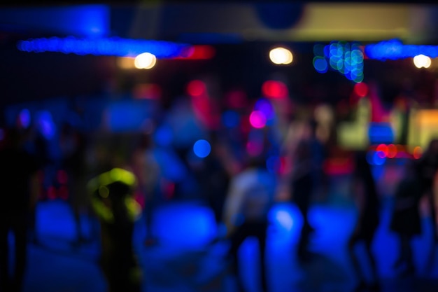 Verschwommenes abstraktes Bild von Leuten, die in einem Nachtclub tanzen. Männer und Frauen tanzen in einem Nachtclub auf dunklem Hintergrund