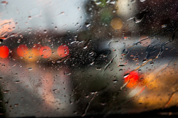 verschwommenes Bild des Verkehrs Blick durch eine Auto-Windschutzscheibe im Regen bedeckt