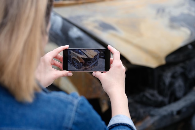 Versicherungsagent oder Ermittler macht nach Brandstiftung ein Foto auf dem Smartphone des Autos