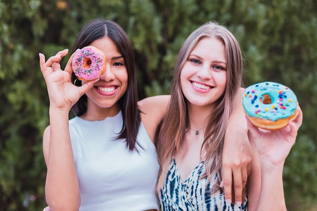 Verspielte Frauen, die Spaß mit süßen Donuts haben