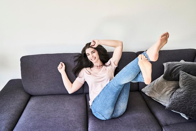 Verspielte junge Frau, die sich auf der Couch amüsiert