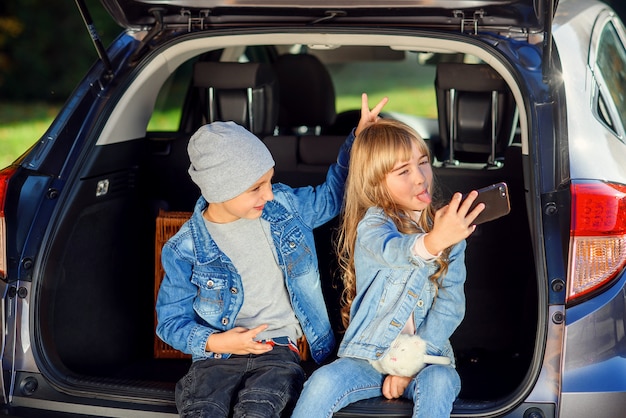 Verspielte Kinder, die Selfie, kleinen Bruder und Schwester nehmen, lustige Gesichter machen und zusammen täuschen, während sie Foto aufnehmen.