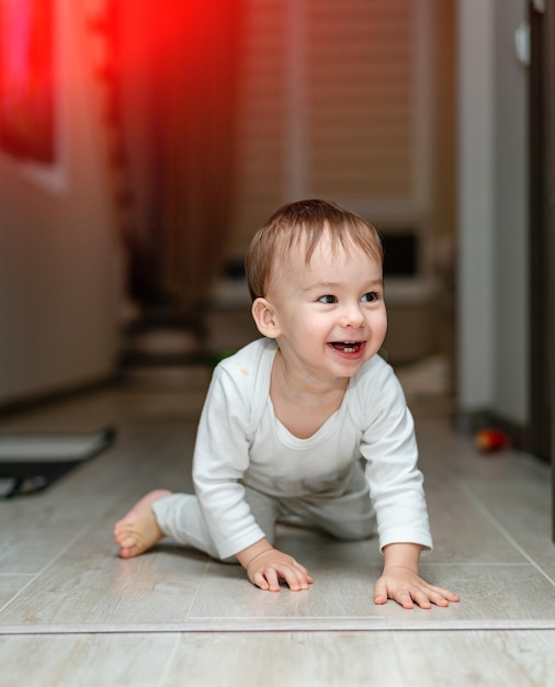 Verspieltes kleines Kind auf dem Boden Freudiger glücklicher Sohn, der Spaß auf dem Boden hat