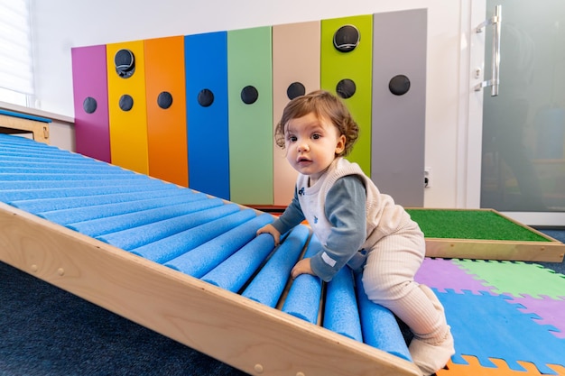 Verspieltes, lustiges, aktives Kind im Vorschulalter Kleines Kind, das auf einem bunten Spielplatz spielt