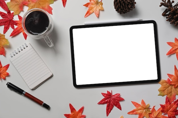 Verspotten Sie digitale Tablette, Kaffeetasse, Tannenzapfen und Ahornblätter auf weißem Tisch.