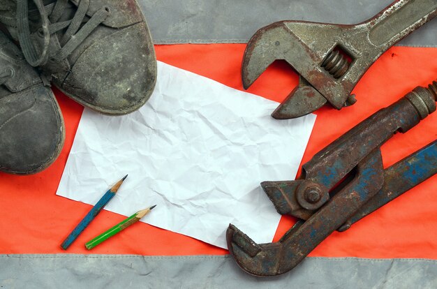 Verstellbare Schraubenschlüssel mit alten Stiefeln und ein Blatt Papier mit zwei Bleistiften