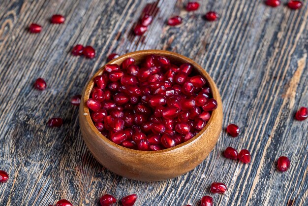 Verstreute Granatapfelkerne auf einem Holzbrett Rote reife Granatapfelkerne werden auf einem Holzschneidebrett verstreut