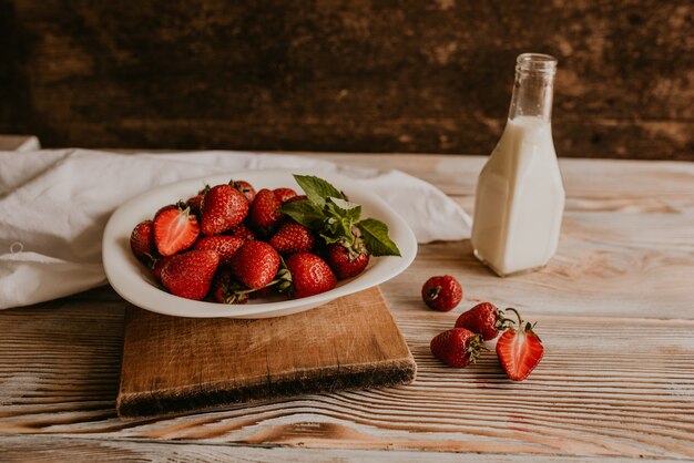 Verstreute saftige frische rote Erdbeeren auf dem Tisch mit Vintage-Planke. Blatt Minze.