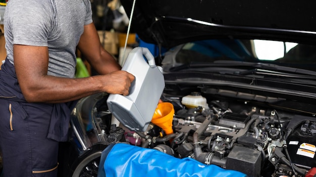 Verter aceite en el motor del automóvil Cerrar el trabajo manual mecánico masculino y el servicio en la estación de servicio de automóviles