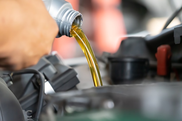 Verter aceite de motor en el motor del automóvil. Aceite fresco vertido durante un cambio de aceite a un automóvil.
