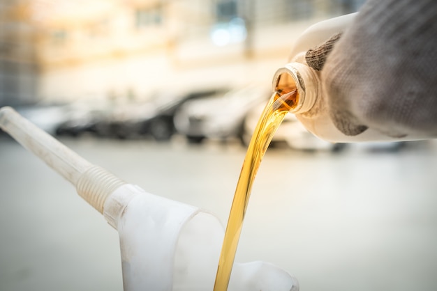 Verter aceite de motor en la sala de máquinas., Aceite de oro durante el cambio de aceite del automóvil en el taller de reparación o centro de servicio., Centro de cuidado interior del automóvil