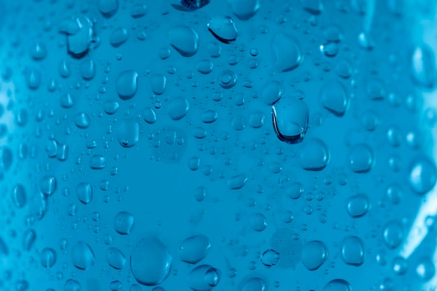 Verter agua de una botella de plástico en un vaso de precipitados sobre un fondo azul.