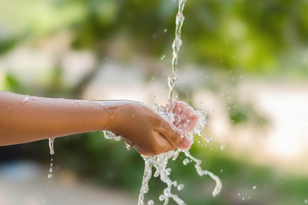 Verter agua en la mano del niño en el fondo de la naturaleza