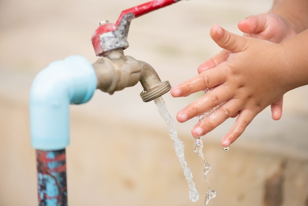 Verter agua en las manos de la niña. Concepto del día del agua