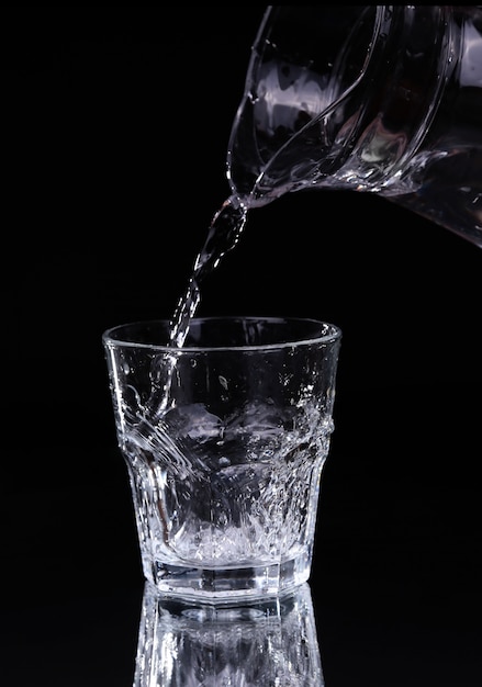 Verter agua en un vaso sobre fondo negro