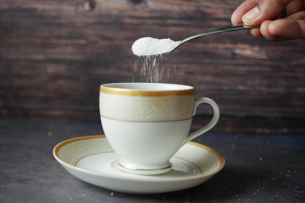 Verter azúcar blanco en una taza de café