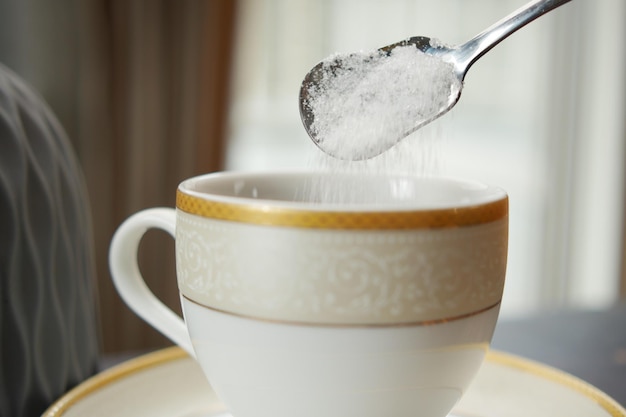 Verter azúcar blanco en una taza de café