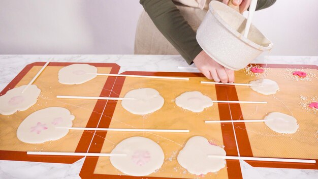 Verter azúcar caramelizada sobre tapetes de silicona para hacer piruletas caseras.
