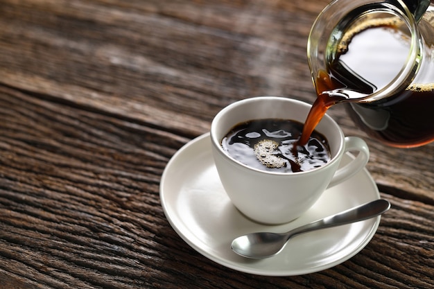 Verter café con humo en una taza sobre fondo de madera