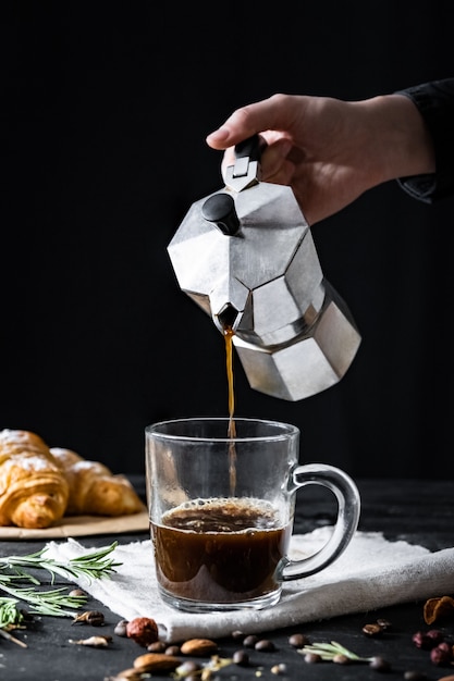 Verter el café de un percolador italiano, tiro en clave baja. Manos masculinas vierten café negro de cervecero moka italiano