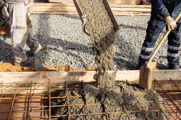 Verter cemento o hormigón con un camión hormigonera sitio de construcción con cimientos de parrillas reforzadas Los trabajadores asientan y nivelan el hormigón en los cimientos