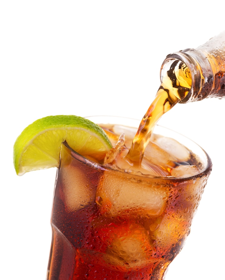 Foto verter cola en vaso con hielo y limón de botella aislado sobre fondo blanco.