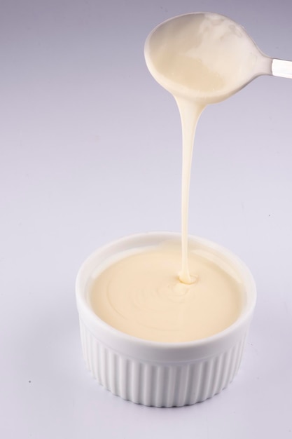 Verter crema de chocolate blanco con cuchara aislado sobre fondo blanco.