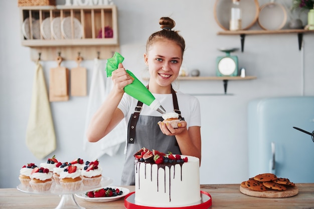 Verter crema. La mujer se encuentra en el interior de la cocina con tarta casera.