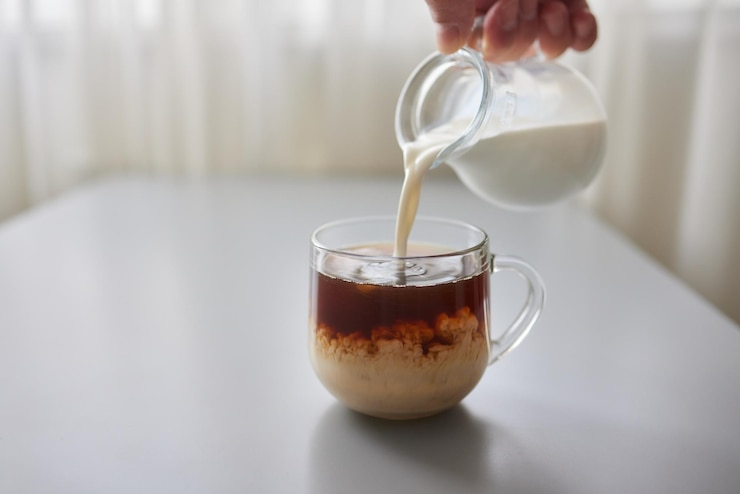 Foto verter creme em uma xícara de café