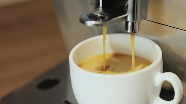 Verter el flujo de café de la máquina en la taza Hacer en casa Espresso caliente Café molido recién molido Bebida bebida para el desayuno