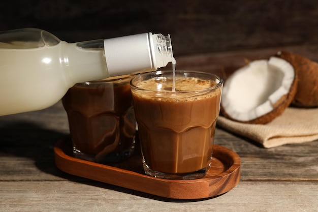 Verter el jarabe de coco en un vaso con un sabroso café en el primer plano de la mesa de madera