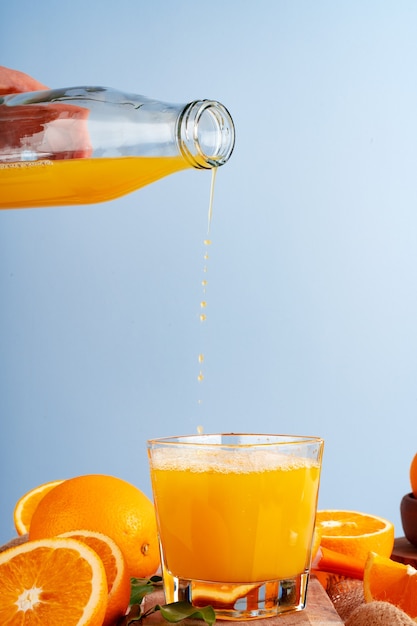 Foto verter el jugo de naranja de la botella en el vaso