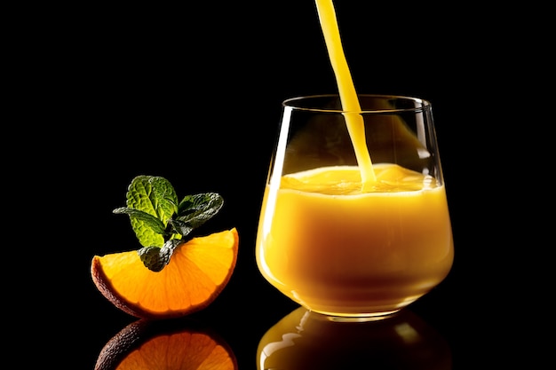 Verter el jugo de naranja en una copa de vidrio sobre fondo negro