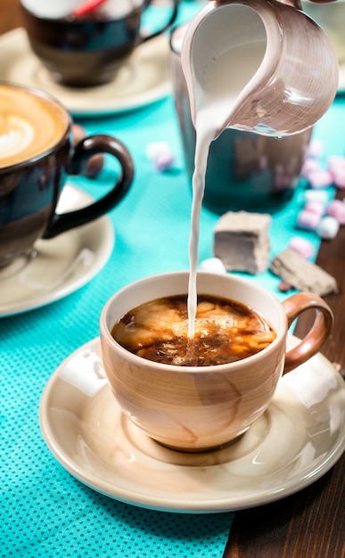 Verter la leche en el café sobre fondo de madera