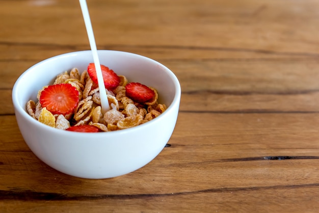 Verter la leche en copos de maíz con fresa. Desayuno con leche y copos de maíz.