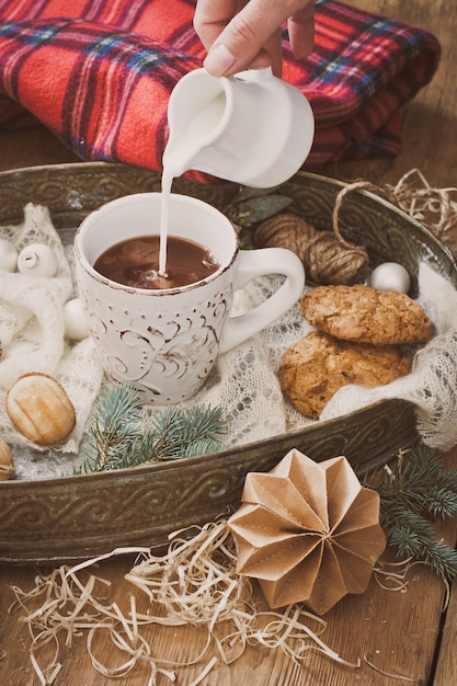 Verter la leche en una taza de cacao y decoraciones navideñas.