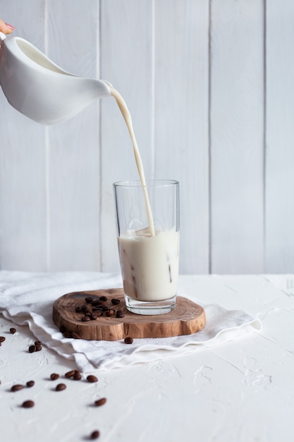 Verter la leche en un vaso con hielo