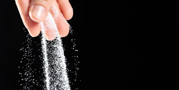 Verter a mano sal de piedra blanca finamente molida fondo negro copiar espacio para el texto