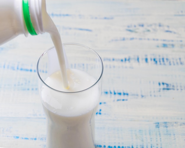 Verter el producto de leche agria kéfir en un vaso sobre un fondo de madera