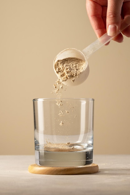 Verter proteína en polvo de una cuchara en un vaso Hacer una bebida de proteína