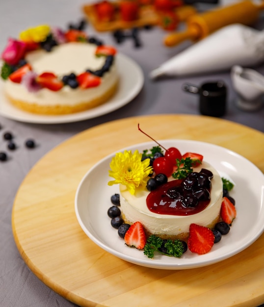Verter salsa de arándanos en un delicioso pastel de queso dulce decorado con bayas frescas y flores en un plato de madera, para un cumpleaños, día de San Valentín y celebración