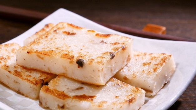 Verter salsa de soja negra en un delicioso pastel de nabo listo para comer, pastel de rábano plato local tradicional chino en el restaurante, de cerca, copie el espacio.